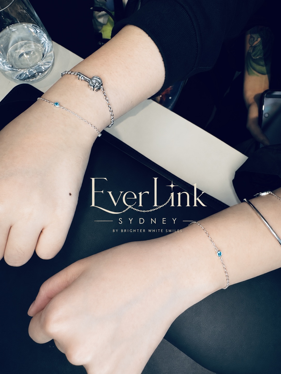 Friends wearing matching silver permanent bracelets with blue charms